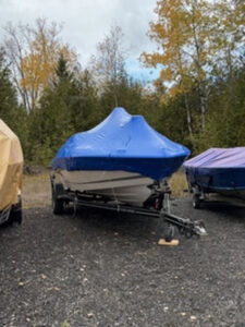 A boat covered in blue shrink wrapping in outdoor storage